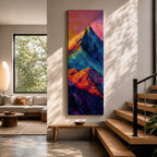 Tall vertical abstract mountain painting with bold colorful peaks in vibrant blue, red, purple, and yellow tones. Thick impasto brushstrokes create dramatic alpine ridges beneath a bright pink and orange sky, forming a modern expressive mountain landscape.