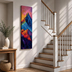 Tall vertical abstract mountain painting with bold colorful peaks in vibrant blue, red, purple, and yellow tones. Thick impasto brushstrokes create dramatic alpine ridges beneath a bright pink and orange sky, forming a modern expressive mountain landscape.
