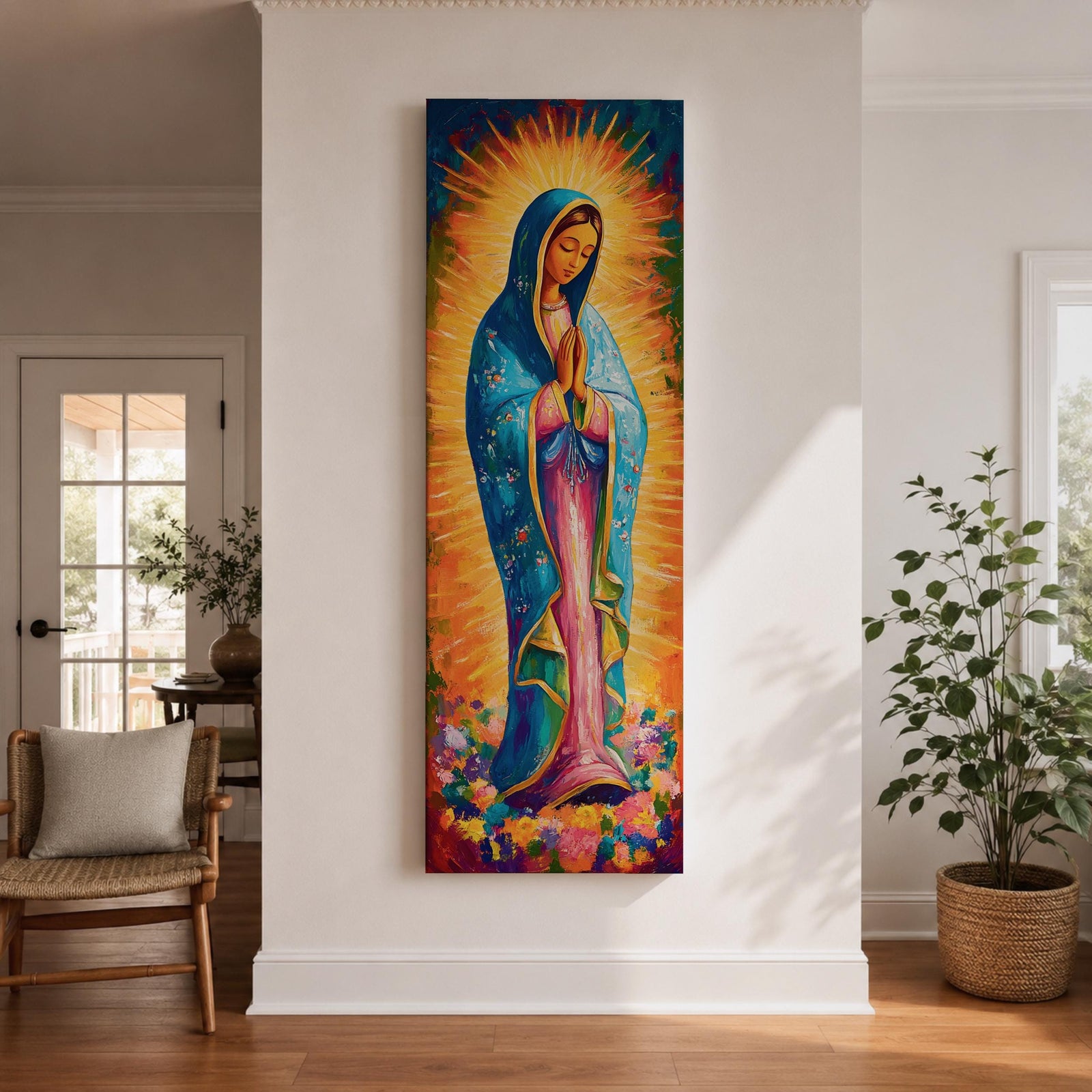 Long vertical painting of the Virgin Mary standing in prayer with hands together, wearing a blue mantle over a pink robe and surrounded by radiant golden rays. Colorful flowers gather at her feet while expressive brushstrokes and vibrant tones create a devotional depiction inspired by the Virgen de Guadalupe iconography.