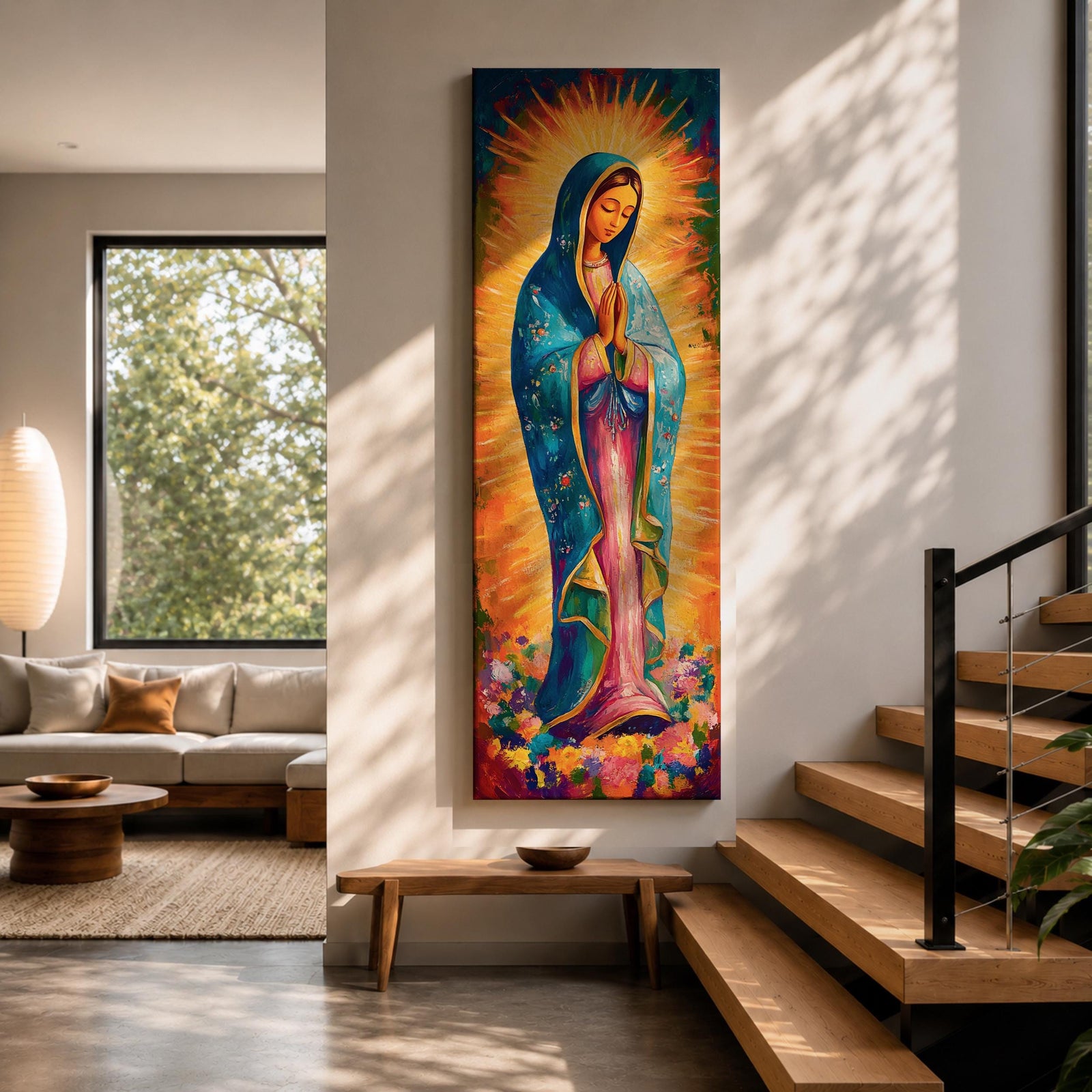 Long vertical painting of the Virgin Mary standing in prayer with hands together, wearing a blue mantle over a pink robe and surrounded by radiant golden rays. Colorful flowers gather at her feet while expressive brushstrokes and vibrant tones create a devotional depiction inspired by the Virgen de Guadalupe iconography.