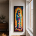 Long vertical painting of the Virgin Mary standing in prayer with hands together, wearing a blue mantle over a pink robe and surrounded by radiant golden rays. Colorful flowers gather at her feet while expressive brushstrokes and vibrant tones create a devotional depiction inspired by the Virgen de Guadalupe iconography.