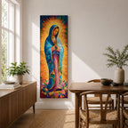 Long vertical painting of the Virgin Mary standing in prayer with hands together, wearing a blue mantle over a pink robe and surrounded by radiant golden rays. Colorful flowers gather at her feet while expressive brushstrokes and vibrant tones create a devotional depiction inspired by the Virgen de Guadalupe iconography.