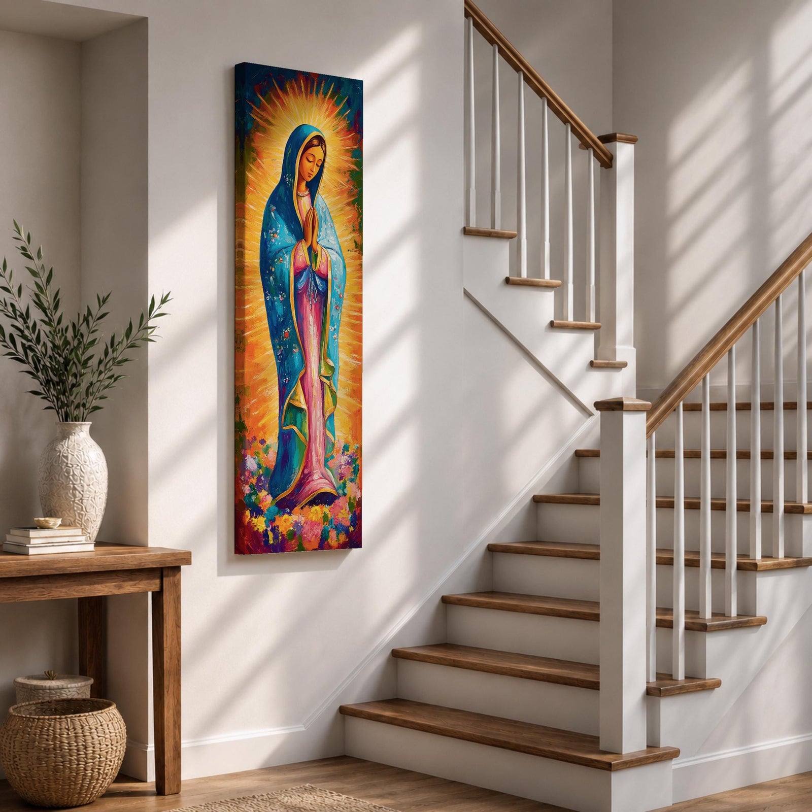 Long vertical painting of the Virgin Mary standing in prayer with hands together, wearing a blue mantle over a pink robe and surrounded by radiant golden rays. Colorful flowers gather at her feet while expressive brushstrokes and vibrant tones create a devotional depiction inspired by the Virgen de Guadalupe iconography.