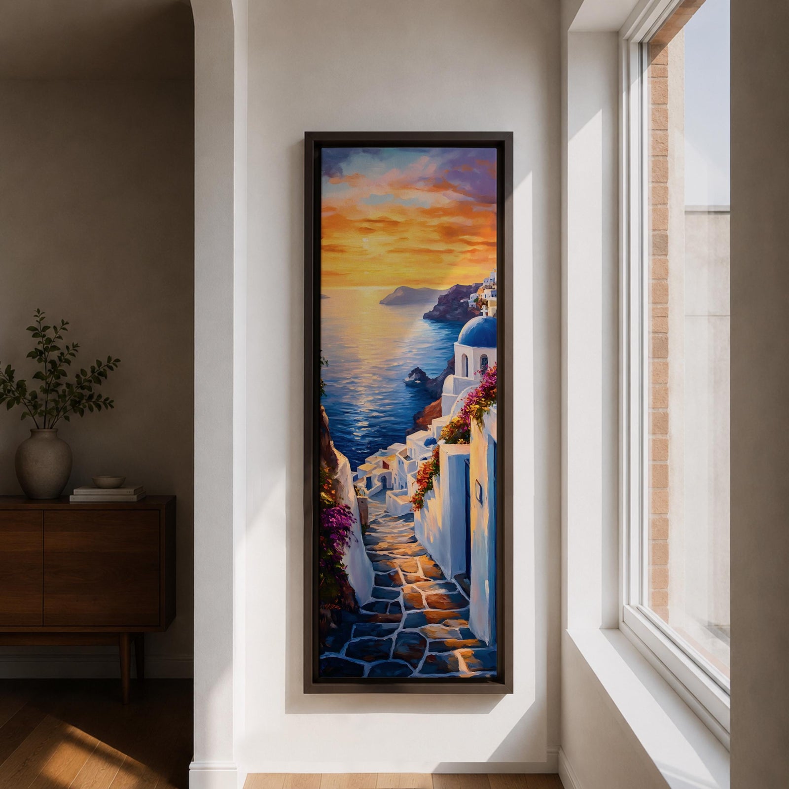 Long vertical painting of a Santorini coastal village with whitewashed buildings and a blue dome church overlooking the sea at sunset. A stone pathway descends between bright white walls toward the shoreline while golden sunlight reflects across calm water and warm clouds fill the sky.