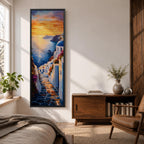 Long vertical painting of a Santorini coastal village with whitewashed buildings and a blue dome church overlooking the sea at sunset. A stone pathway descends between bright white walls toward the shoreline while golden sunlight reflects across calm water and warm clouds fill the sky.