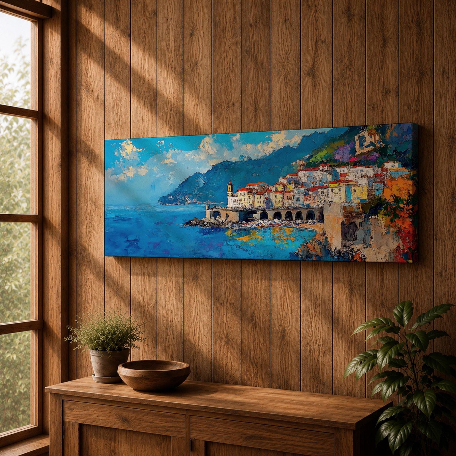 Panoramic Mediterranean coastal painting of the Amalfi Coast featuring colorful hillside houses overlooking bright blue sea. A stone harbor with arches and boats sits along the shoreline while mountains rise in the background beneath a clear sky with scattered clouds across the wide horizontal seaside composition.