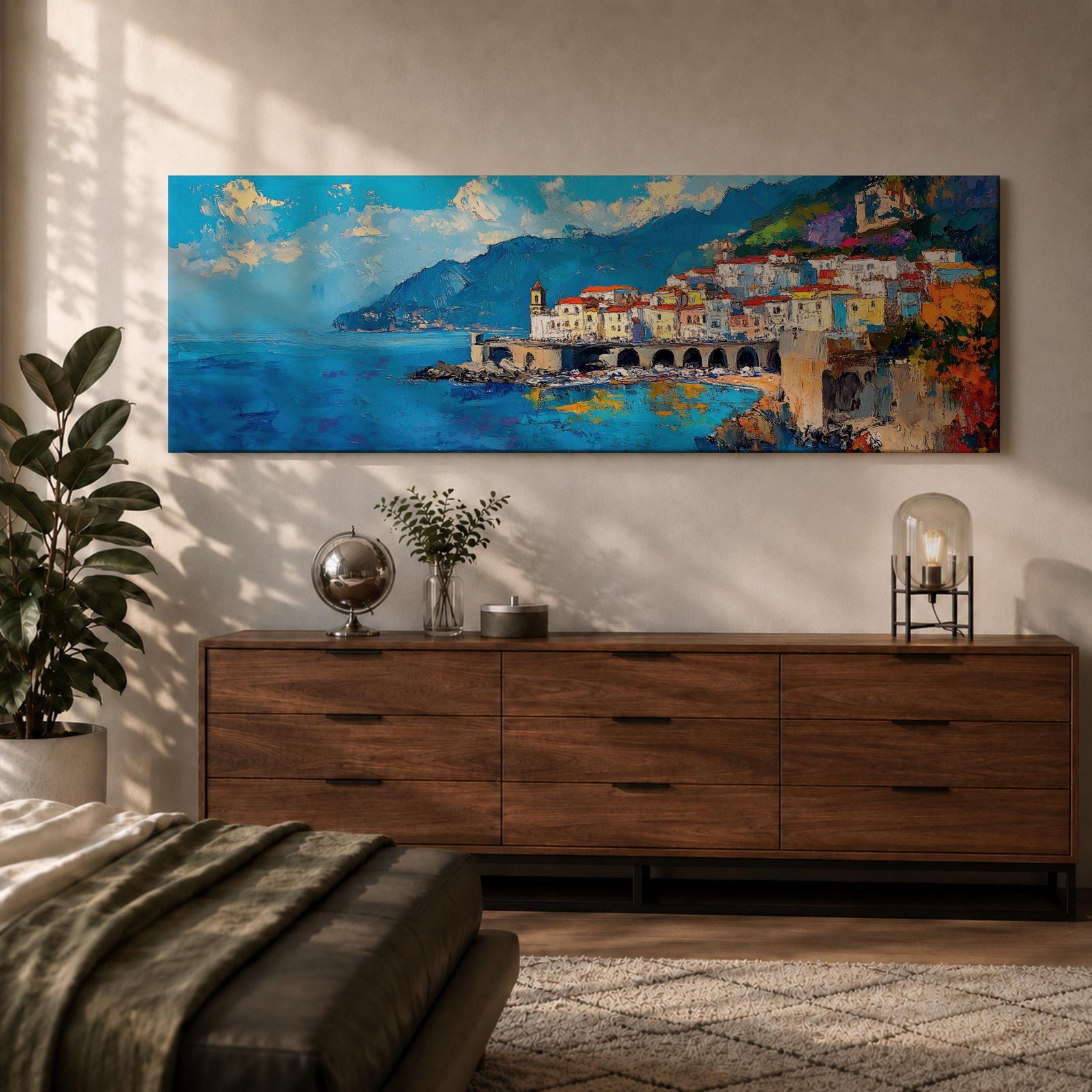 Panoramic Mediterranean coastal painting of the Amalfi Coast featuring colorful hillside houses overlooking bright blue sea. A stone harbor with arches and boats sits along the shoreline while mountains rise in the background beneath a clear sky with scattered clouds across the wide horizontal seaside composition.