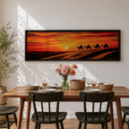 Panoramic desert sunset painting featuring a silhouette caravan of camels and riders walking along rolling sand dunes beneath a glowing red and orange sky. The low sun sits near the horizon while layered desert dunes stretch into the distance, creating a dramatic wide composition across the desert landscape.