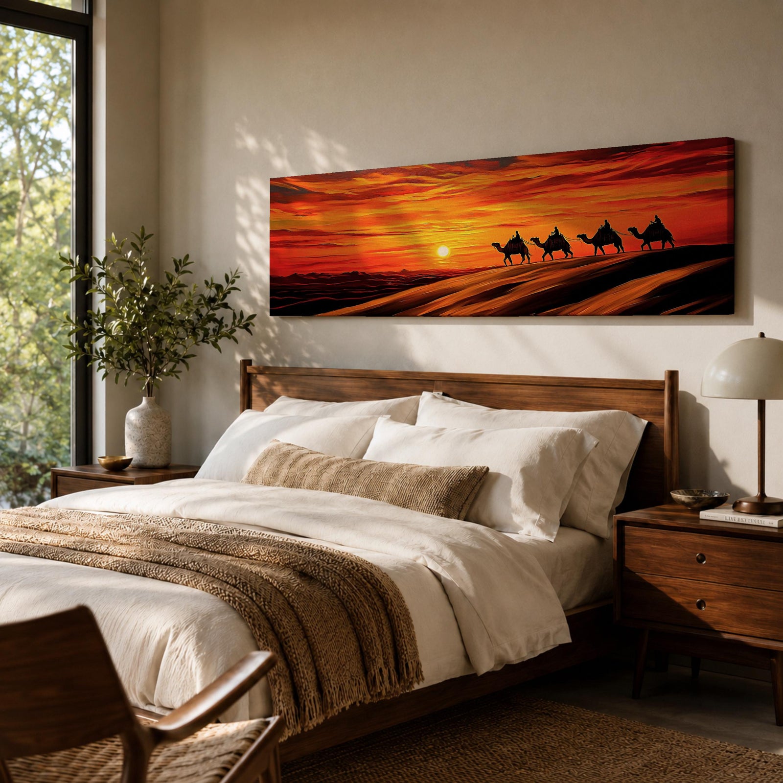 Panoramic desert sunset painting featuring a silhouette caravan of camels and riders walking along rolling sand dunes beneath a glowing red and orange sky. The low sun sits near the horizon while layered desert dunes stretch into the distance, creating a dramatic wide composition across the desert landscape.