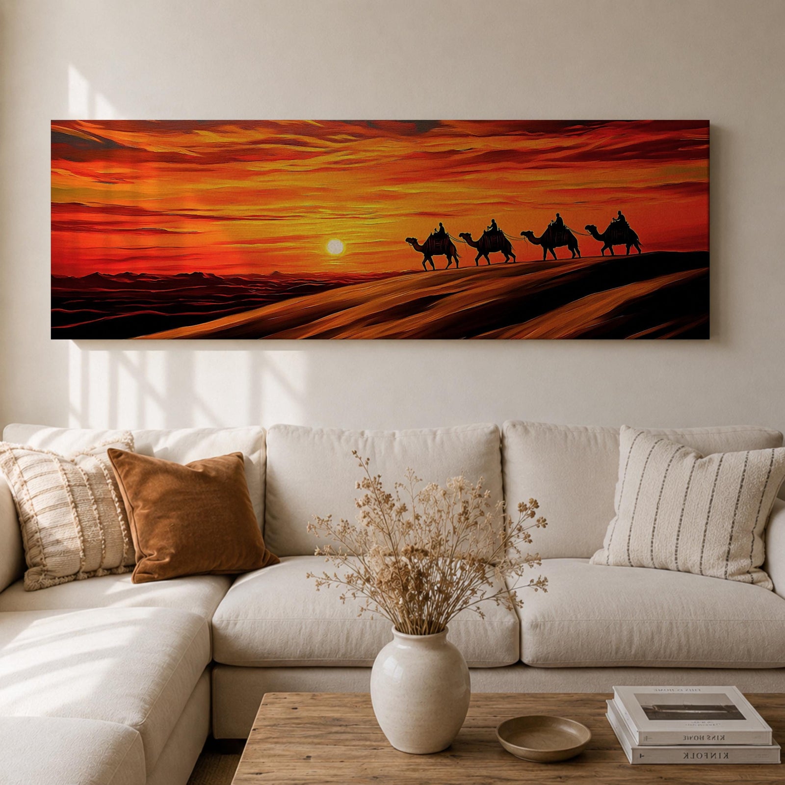 Panoramic desert sunset painting featuring a silhouette caravan of camels and riders walking along rolling sand dunes beneath a glowing red and orange sky. The low sun sits near the horizon while layered desert dunes stretch into the distance, creating a dramatic wide composition across the desert landscape.