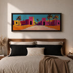 Panoramic desert village painting showing colorful Moroccan kasbah buildings in bright pink and warm ochre tones with tall palm trees lining a sandy road. Bold textured brushstrokes and vibrant colors create a lively North African scene beneath a clear blue sky across the wide horizontal composition.