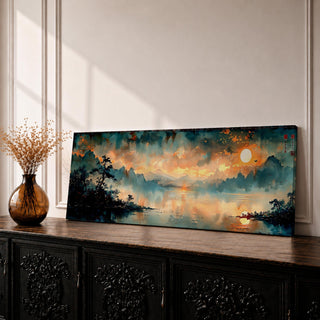 Panoramic Chinese landscape painting of misty mountains rising above a tranquil lake at sunset with warm orange light reflecting across the water. Dark tree silhouettes frame the shoreline while distant peaks fade into atmospheric haze beneath dramatic clouds in a traditional oriental scenery composition.