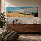 Panoramic wheat field landscape painting showing rolling golden farmland stretching across hills beneath a bright blue sky with scattered clouds. Textured brushstrokes depict tall wheat grasses in the foreground leading toward layered countryside fields, tree clusters, and distant hills across the wide rural horizon.