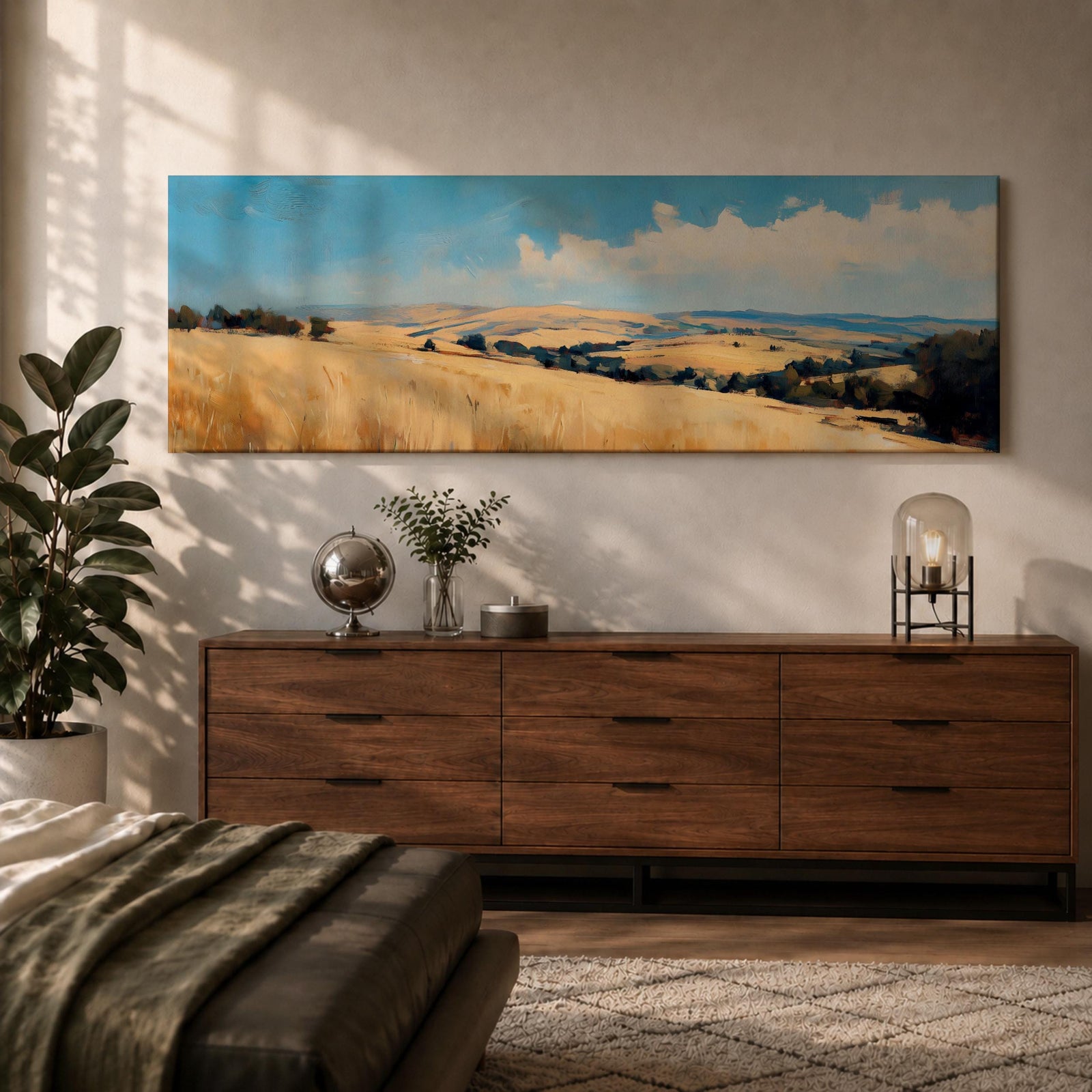 Panoramic wheat field landscape painting showing rolling golden farmland stretching across hills beneath a bright blue sky with scattered clouds. Textured brushstrokes depict tall wheat grasses in the foreground leading toward layered countryside fields, tree clusters, and distant hills across the wide rural horizon.