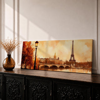 A long panoramic watercolor style painting of the Eiffel Tower rising above the Paris skyline beside the Seine River. Warm autumn foliage frames the scene while a bridge crosses the river and historic buildings sit beneath a glowing sky, creating a romantic Paris cityscape in a wide horizontal composition.