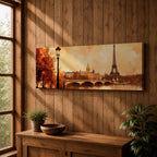 A long panoramic watercolor style painting of the Eiffel Tower rising above the Paris skyline beside the Seine River. Warm autumn foliage frames the scene while a bridge crosses the river and historic buildings sit beneath a glowing sky, creating a romantic Paris cityscape in a wide horizontal composition.