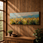Panoramic wildflower meadow painting featuring tall golden grasses mixed with scattered red, yellow, and blue flowers swaying across an open field. Loose textured brushstrokes create depth through the meadow while a soft blue sky and distant horizon stretch across the wide landscape composition.
