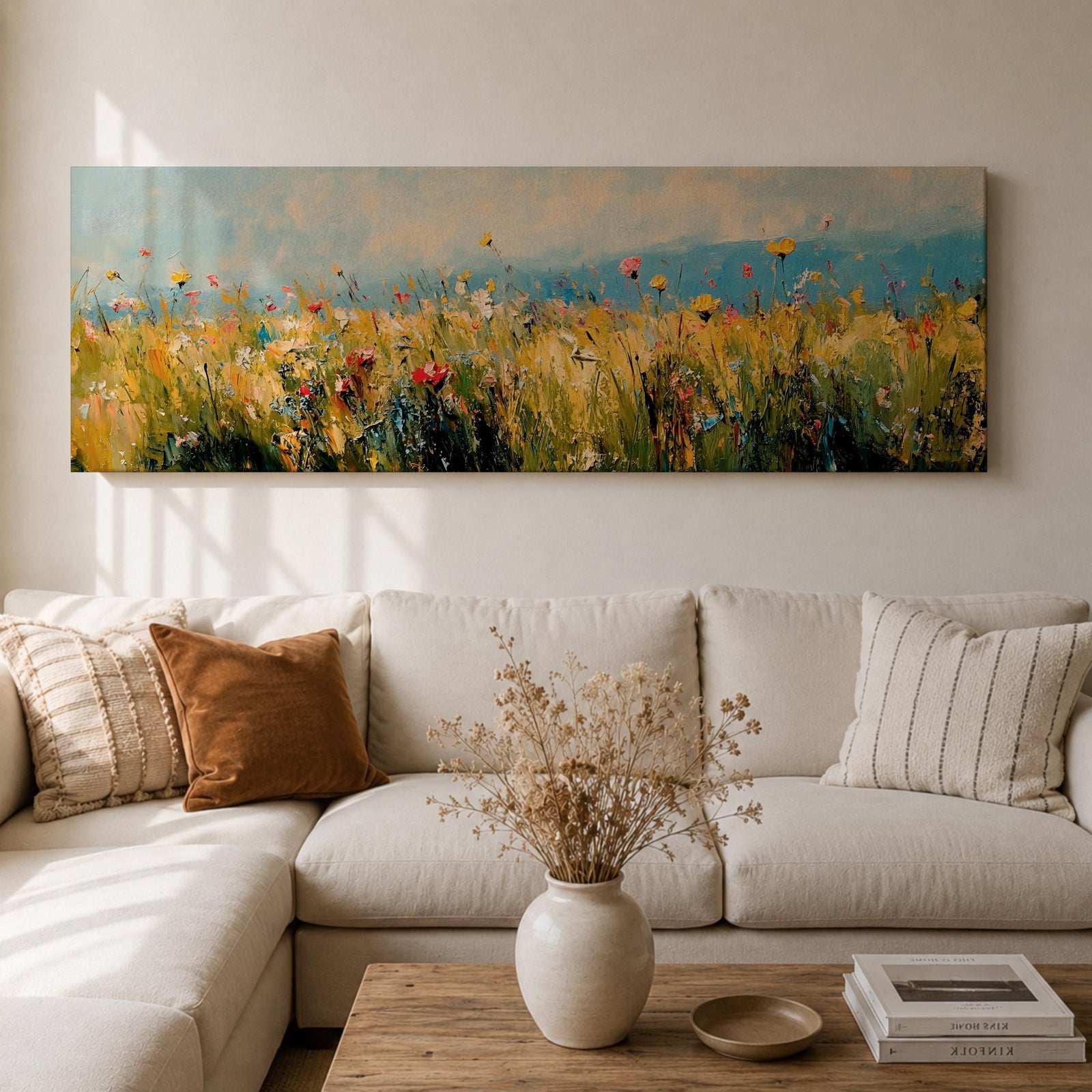 Panoramic wildflower meadow painting featuring tall golden grasses mixed with scattered red, yellow, and blue flowers swaying across an open field. Loose textured brushstrokes create depth through the meadow while a soft blue sky and distant horizon stretch across the wide landscape composition.