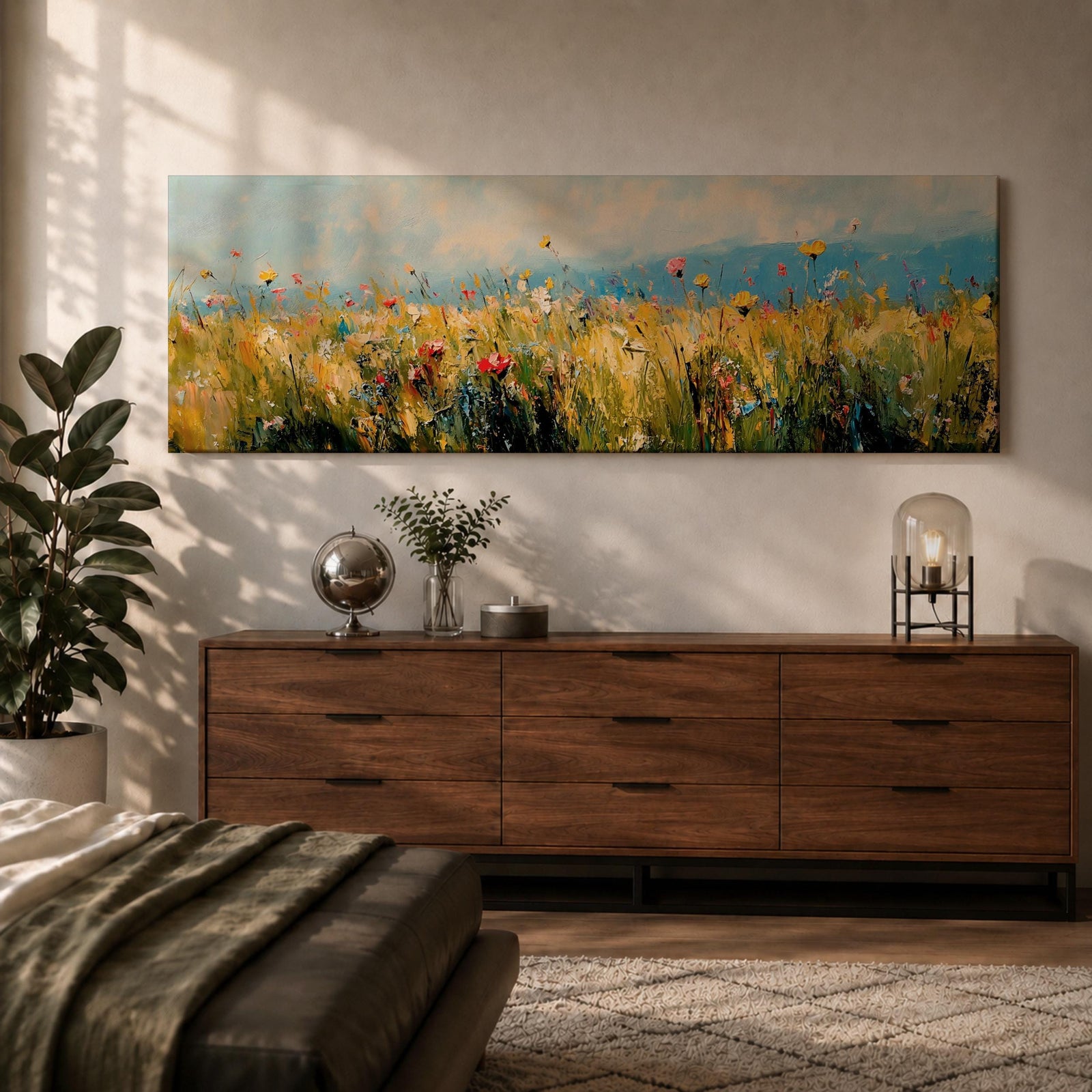Panoramic wildflower meadow painting featuring tall golden grasses mixed with scattered red, yellow, and blue flowers swaying across an open field. Loose textured brushstrokes create depth through the meadow while a soft blue sky and distant horizon stretch across the wide landscape composition.