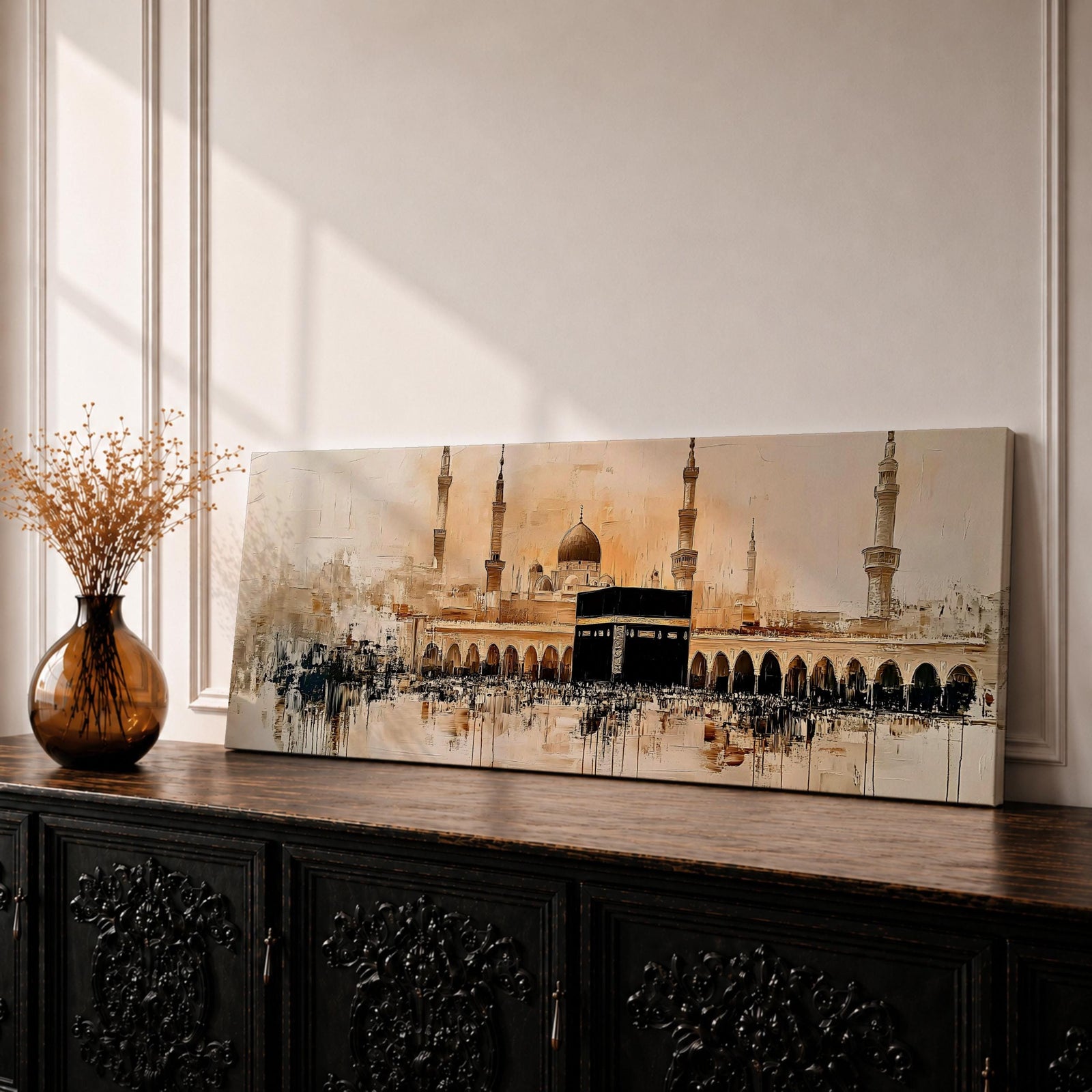 Panoramic painting of the Kaaba at Masjid Al Haram in Mecca surrounded by mosque arches and tall minarets. The sacred black cube stands at the center of a wide courtyard with crowds gathered around while warm golden tones and architectural details stretch across the expansive skyline.
