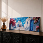 Panoramic painting of a Santorini village featuring whitewashed buildings with blue doors and a domed church along a sunlit stone pathway. Pink bougainvillea flowers frame the scene while bright blue sky and distant Aegean Sea appear beyond the island architecture across the wide composition.