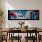 Panoramic painting of a Santorini village featuring whitewashed buildings with blue doors and a domed church along a sunlit stone pathway. Pink bougainvillea flowers frame the scene while bright blue sky and distant Aegean Sea appear beyond the island architecture across the wide composition.