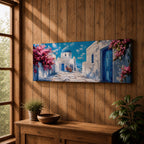 Panoramic painting of a Santorini village featuring whitewashed buildings with blue doors and a domed church along a sunlit stone pathway. Pink bougainvillea flowers frame the scene while bright blue sky and distant Aegean Sea appear beyond the island architecture across the wide composition.