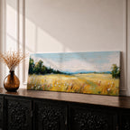 Panoramic countryside landscape painting showing a wide golden field filled with tall grasses and scattered wildflowers. A tree line borders the meadow while distant hills stretch across the horizon beneath a soft blue sky with light clouds across the expansive rural scene.