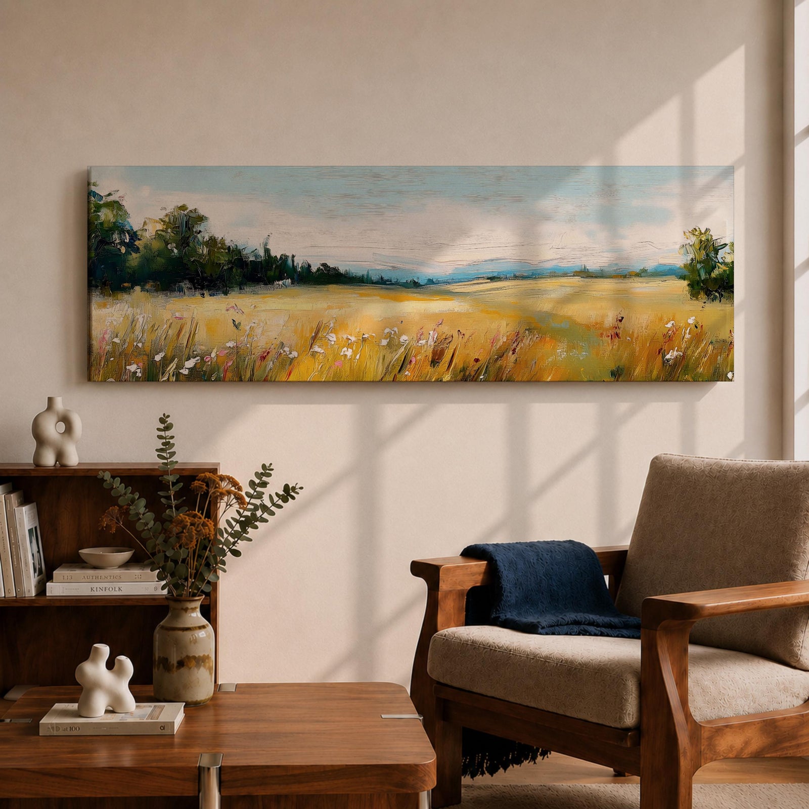 Panoramic countryside landscape painting showing a wide golden field filled with tall grasses and scattered wildflowers. A tree line borders the meadow while distant hills stretch across the horizon beneath a soft blue sky with light clouds across the expansive rural scene.