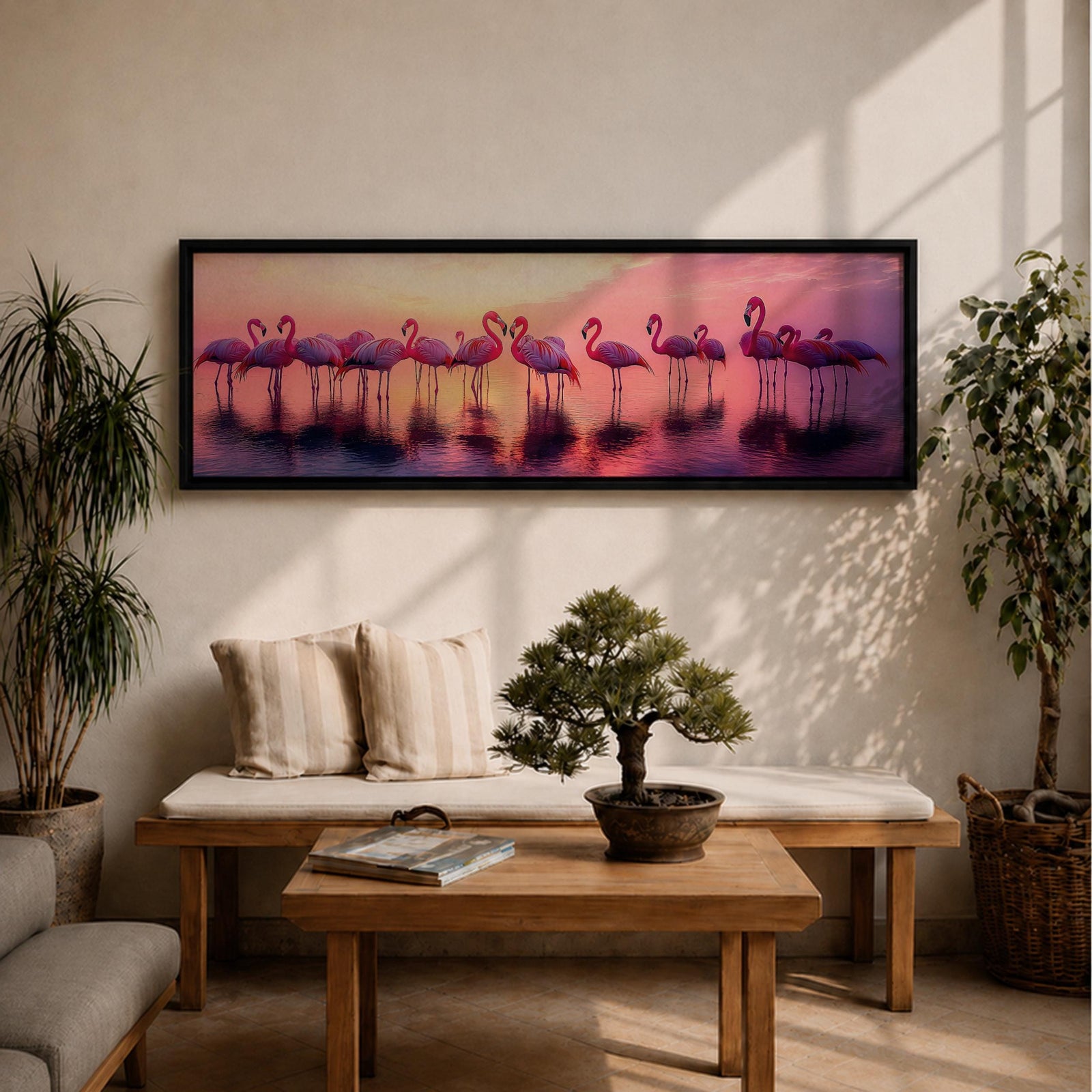 Panoramic artwork showing a flock of flamingos standing in shallow reflective water at sunset. The long horizontal composition features pink birds mirrored in the calm lake surface with glowing orange, purple, and magenta sky tones behind them, creating a tropical waterscape with silhouettes and soft reflections stretching across the scene.