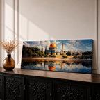 Panoramic canvas artwork depicting the Dome of the Rock in Jerusalem with its iconic golden dome and blue tiled octagonal structure rising above surrounding trees and historic buildings, reflected in calm water in the foreground beneath a bright sky filled with scattered clouds, rendered in a detailed landscape style emphasizing the architecture and skyline of the sacred site.