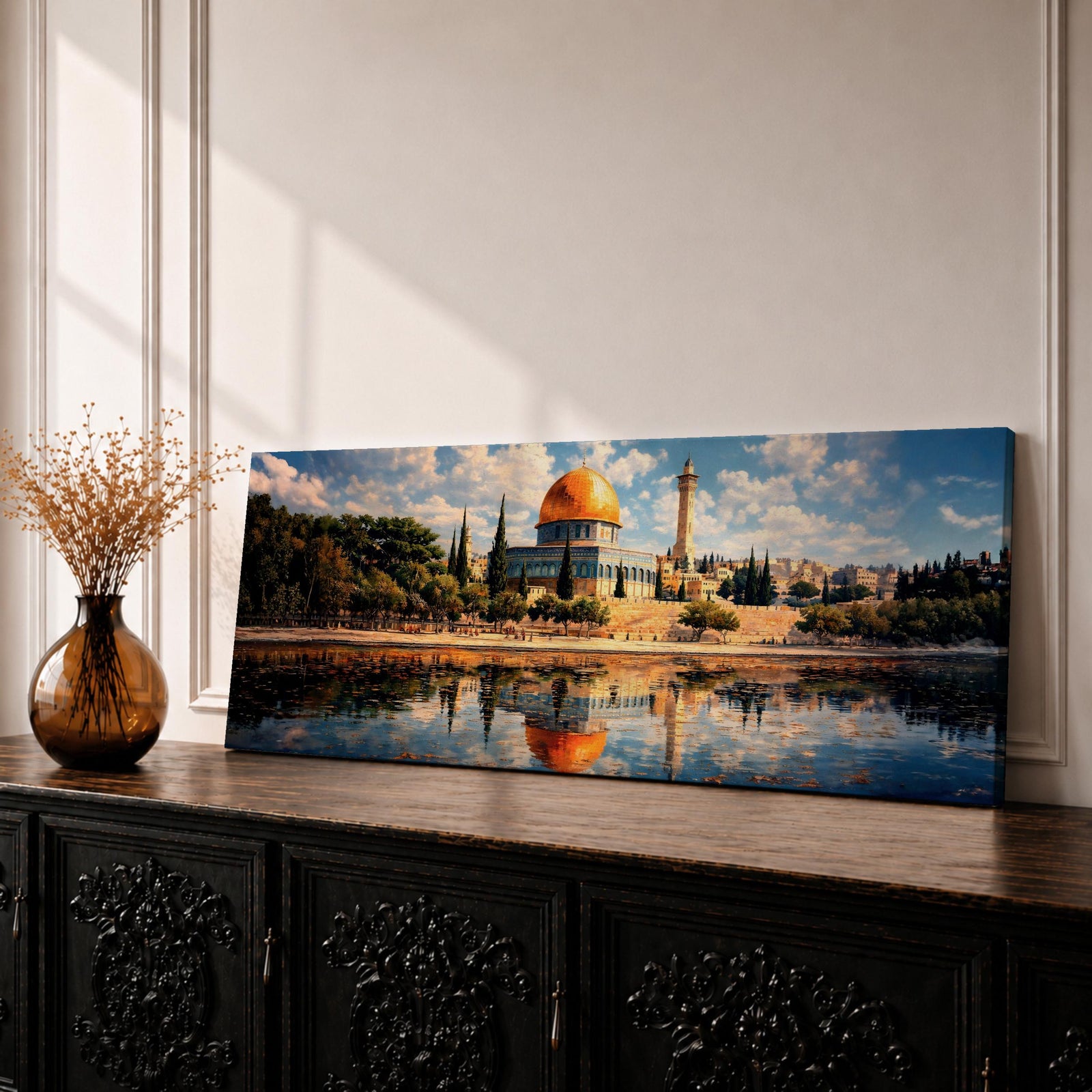 Panoramic canvas artwork depicting the Dome of the Rock in Jerusalem with its iconic golden dome and blue tiled octagonal structure rising above surrounding trees and historic buildings, reflected in calm water in the foreground beneath a bright sky filled with scattered clouds, rendered in a detailed landscape style emphasizing the architecture and skyline of the sacred site.