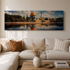 Panoramic canvas artwork depicting the Dome of the Rock in Jerusalem with its iconic golden dome and blue tiled octagonal structure rising above surrounding trees and historic buildings, reflected in calm water in the foreground beneath a bright sky filled with scattered clouds, rendered in a detailed landscape style emphasizing the architecture and skyline of the sacred site.