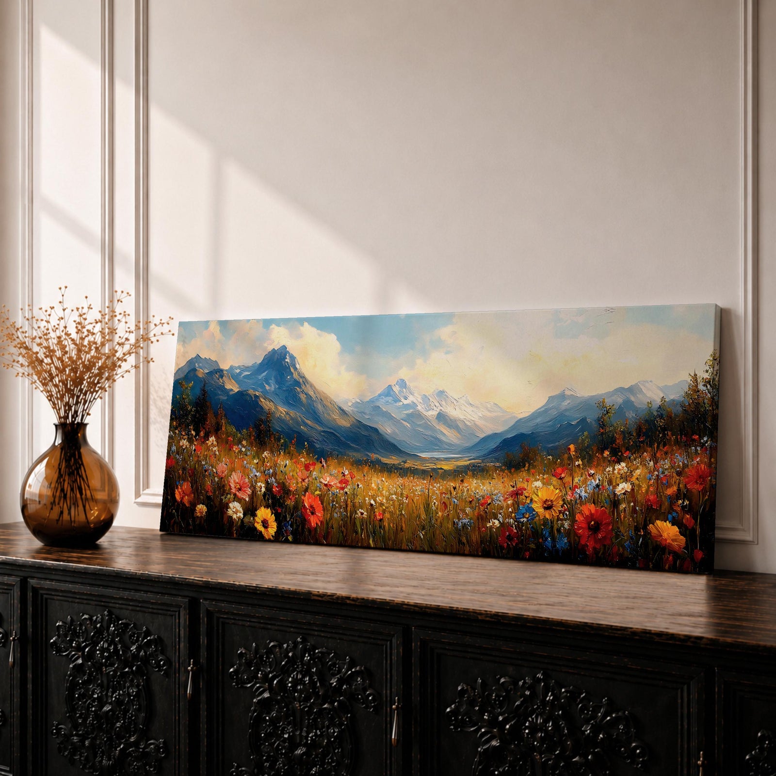Panoramic landscape painting depicting a wide alpine meadow filled with colorful wildflowers in the foreground leading toward distant snow capped mountains, with rolling hills and soft clouds above, rendered in warm natural tones and expressive brushstrokes forming a sweeping scenic mountain vista.