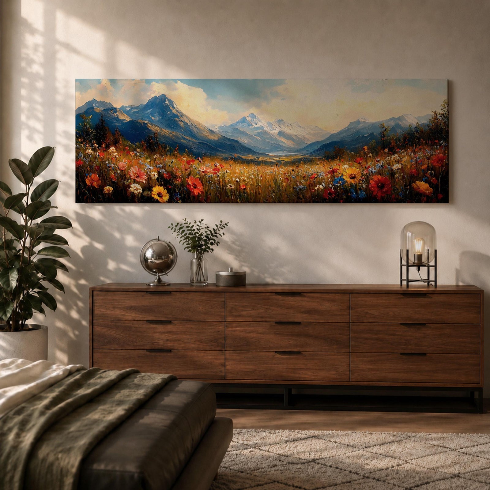 Panoramic landscape painting depicting a wide alpine meadow filled with colorful wildflowers in the foreground leading toward distant snow capped mountains, with rolling hills and soft clouds above, rendered in warm natural tones and expressive brushstrokes forming a sweeping scenic mountain vista.