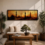 Panoramic artwork depicting a dramatic skyline of mosque domes and tall minarets silhouetted against a glowing golden sunset sky, with warm amber and orange tones diffused through atmospheric haze creating a striking Islamic architectural horizon.