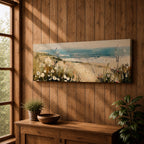 A long panoramic coastal painting showing sandy dunes covered with wild grasses and small white flowers overlooking a calm ocean shoreline. Soft waves roll toward the beach beneath a pale blue sky while textured brush strokes create a peaceful seascape landscape stretching across a wide horizontal composition.