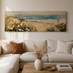 A long panoramic coastal painting showing sandy dunes covered with wild grasses and small white flowers overlooking a calm ocean shoreline. Soft waves roll toward the beach beneath a pale blue sky while textured brush strokes create a peaceful seascape landscape stretching across a wide horizontal composition.