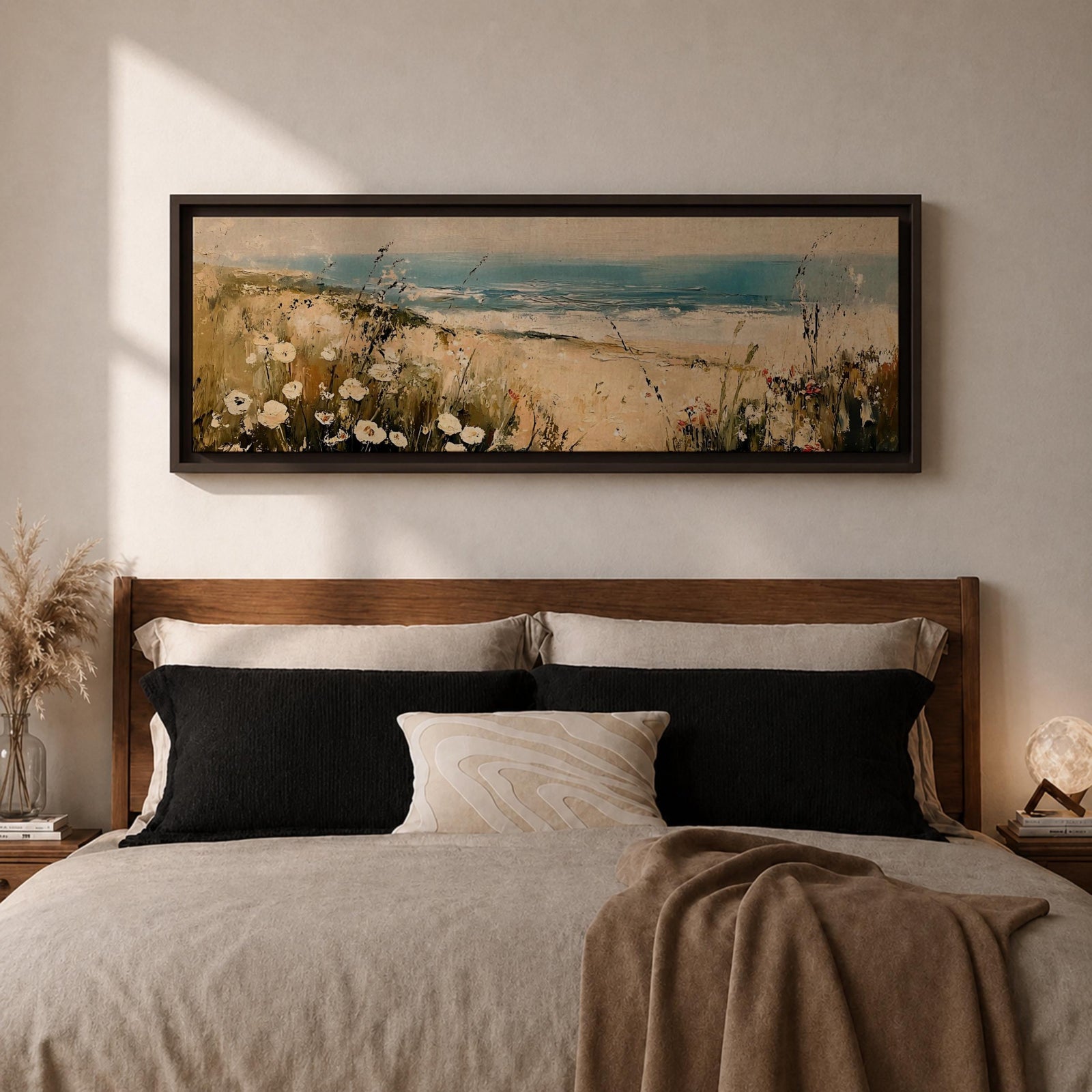 A long panoramic coastal painting showing sandy dunes covered with wild grasses and small white flowers overlooking a calm ocean shoreline. Soft waves roll toward the beach beneath a pale blue sky while textured brush strokes create a peaceful seascape landscape stretching across a wide horizontal composition.
