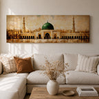 A long panoramic painting of the Prophet’s Mosque in Medina featuring the iconic green dome centered above grand archways and courtyards. Tall minarets rise on both sides while warm golden tones and textured brush strokes depict the historic Islamic mosque complex in a wide horizontal architectural composition.