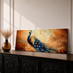 A long panoramic painting of a vibrant peacock standing in an autumn landscape with its long blue and gold tail feathers flowing across the composition. The bird displays detailed eye patterned plumage while warm sunset tones and delicate foliage create a serene nature scene in a wide horizontal format.