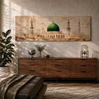 A long panoramic painting of the Green Dome of Masjid Nabawi in Medina rising above elegant mosque arches and courtyards. Tall slender minarets frame the sacred structure while soft beige and golden tones create a historic Islamic architectural scene centered on the iconic green dome in a wide horizontal composition.
