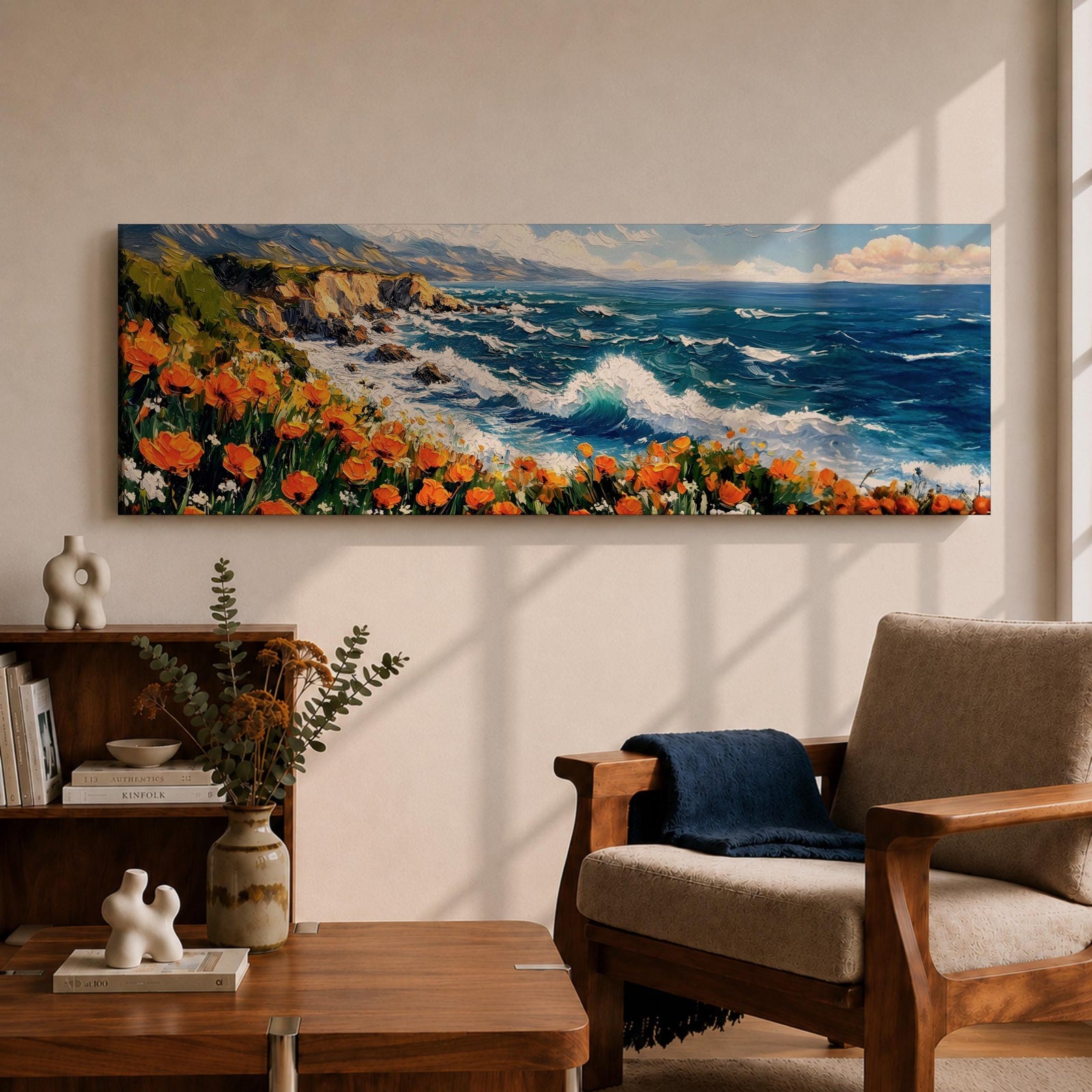 A long panoramic coastal painting showing ocean waves crashing against rocky cliffs while bright orange wildflowers bloom along the shoreline. Deep blue water and white sea foam move toward the coast beneath a clear sky, creating a vibrant seascape landscape in a wide horizontal composition.