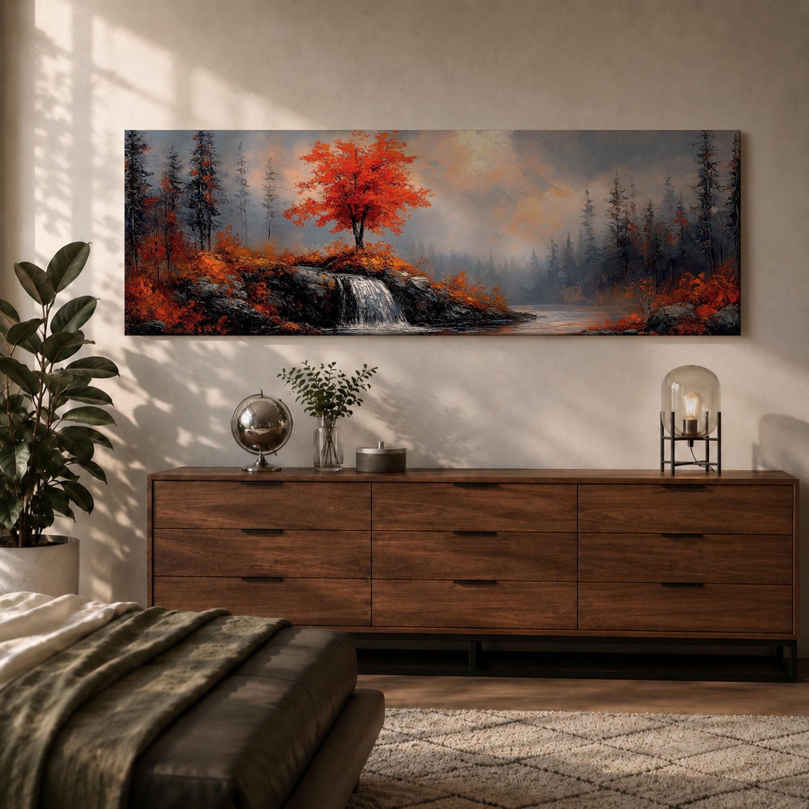 A long panoramic landscape painting showing a small waterfall flowing over rocky cliffs beneath a vivid red autumn tree. Surrounding forest trees fade into misty blue tones while bright fall foliage and rugged stones frame the stream, forming a tranquil woodland scene across a wide horizontal composition.
