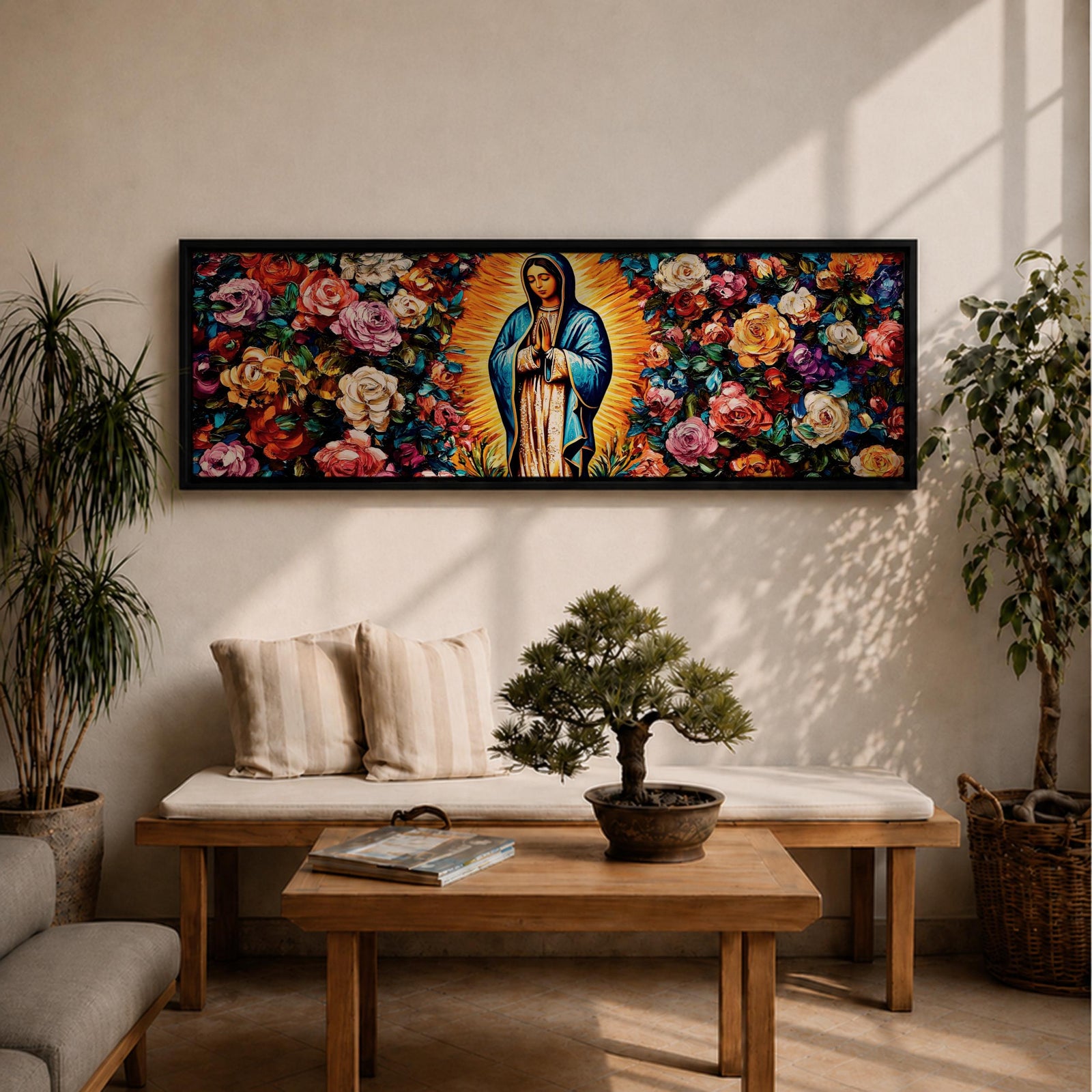 A long panoramic painting of Mary of Guadalupe standing in prayer with hands folded and head bowed, surrounded by radiant golden rays. She wears a blue mantle over a rose colored gown while vibrant roses and colorful flowers fill the background, creating a devotional Catholic Marian image across a wide horizontal composition.