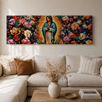 A long panoramic painting of Mary of Guadalupe standing in prayer with hands folded and head bowed, surrounded by radiant golden rays. She wears a blue mantle over a rose colored gown while vibrant roses and colorful flowers fill the background, creating a devotional Catholic Marian image across a wide horizontal composition.