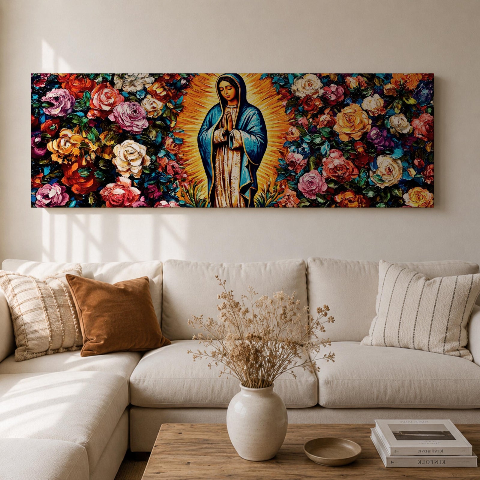 A long panoramic painting of Mary of Guadalupe standing in prayer with hands folded and head bowed, surrounded by radiant golden rays. She wears a blue mantle over a rose colored gown while vibrant roses and colorful flowers fill the background, creating a devotional Catholic Marian image across a wide horizontal composition.