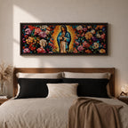 A long panoramic painting of Mary of Guadalupe standing in prayer with hands folded and head bowed, surrounded by radiant golden rays. She wears a blue mantle over a rose colored gown while vibrant roses and colorful flowers fill the background, creating a devotional Catholic Marian image across a wide horizontal composition.