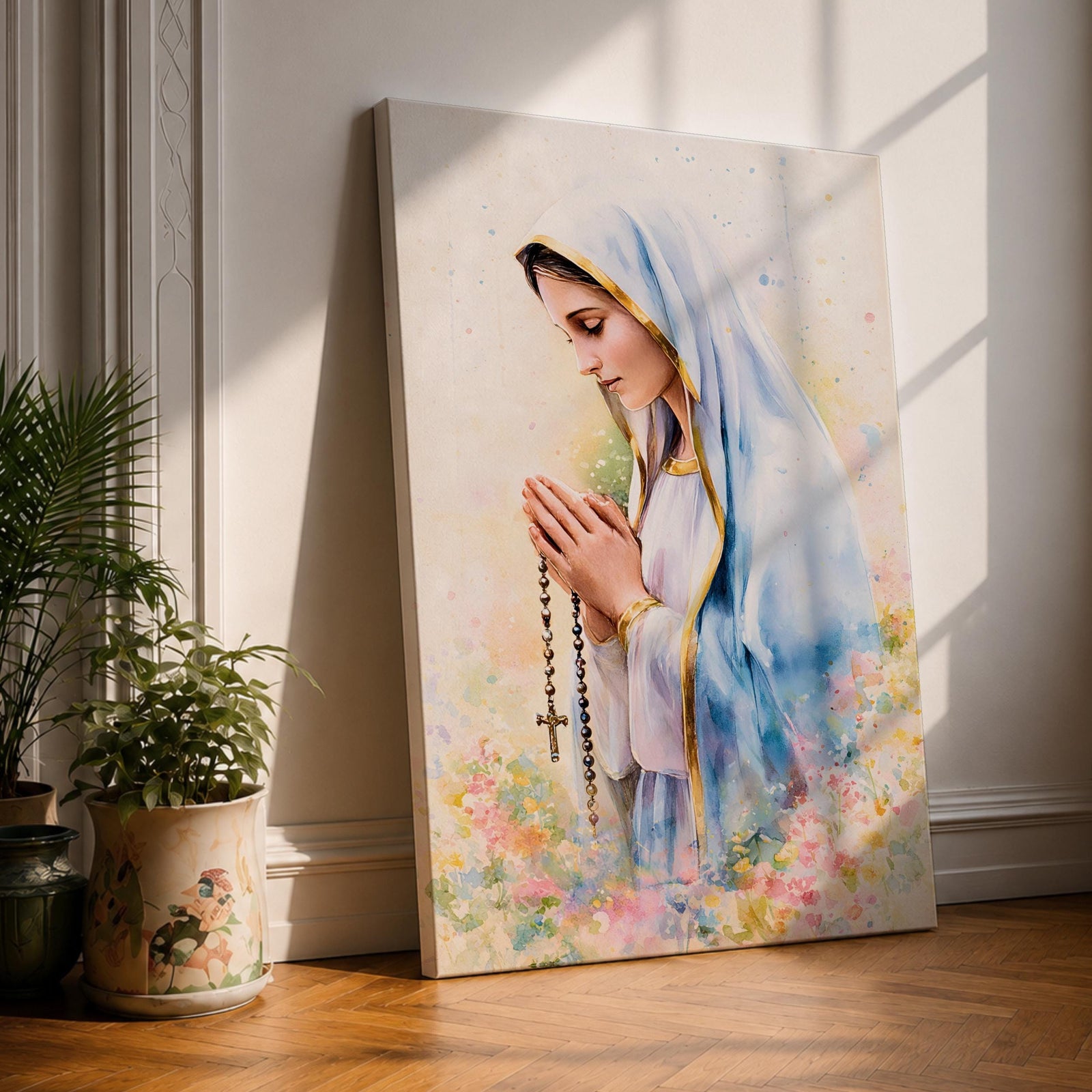 A watercolor style framed canvas depicting Virgin Mary in profile, wearing a blue and white veil with gold trim, holding a rosary and praying, surrounded by soft floral colors and a gentle light background.