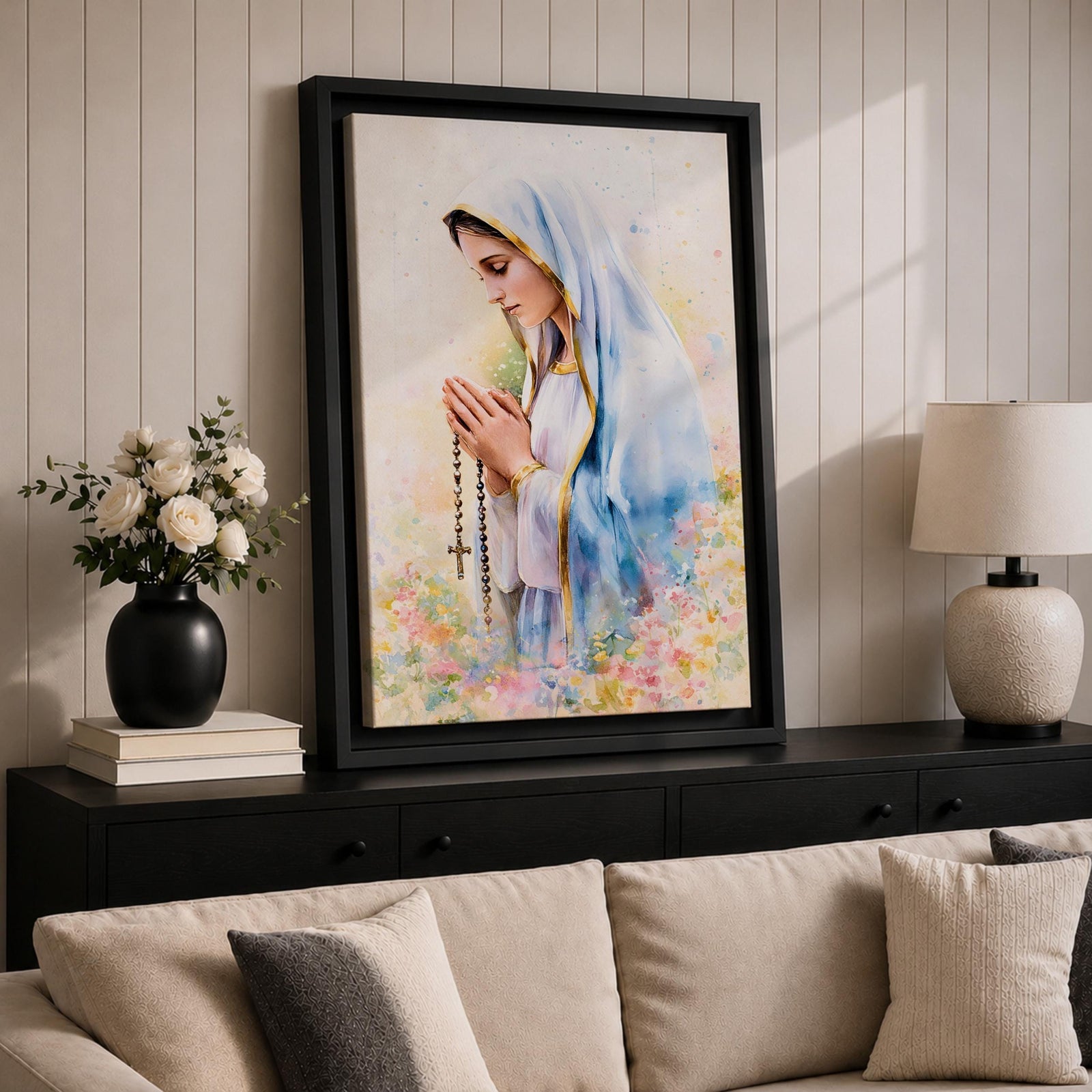 A watercolor style framed canvas depicting Virgin Mary in profile, wearing a blue and white veil with gold trim, holding a rosary and praying, surrounded by soft floral colors and a gentle light background.